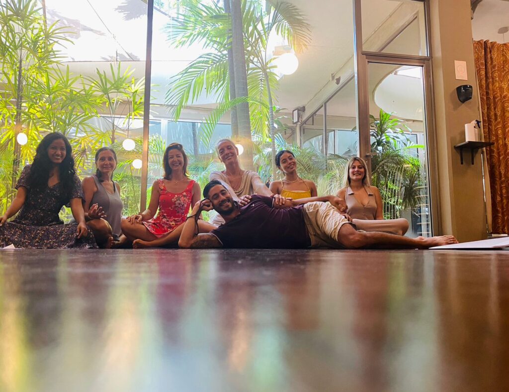 Lisa with her yoga teacher training group in Playa del Carmen, seated together in a bright, plant-filled studio